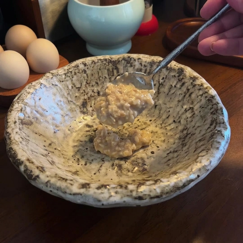 Ein Löffel voll Miso-Sesam-Paste in einer leeren Keramikschüssel.