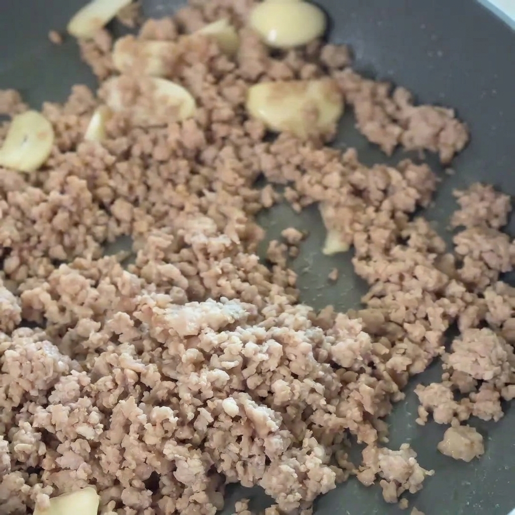 Rote Chilipaste wird unter die Fleisch-Knoblauch-Mischung gerührt.