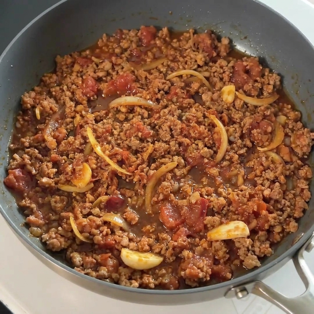 Sojasauce wird über das gewürzte Fleisch in der Pfanne gegossen.