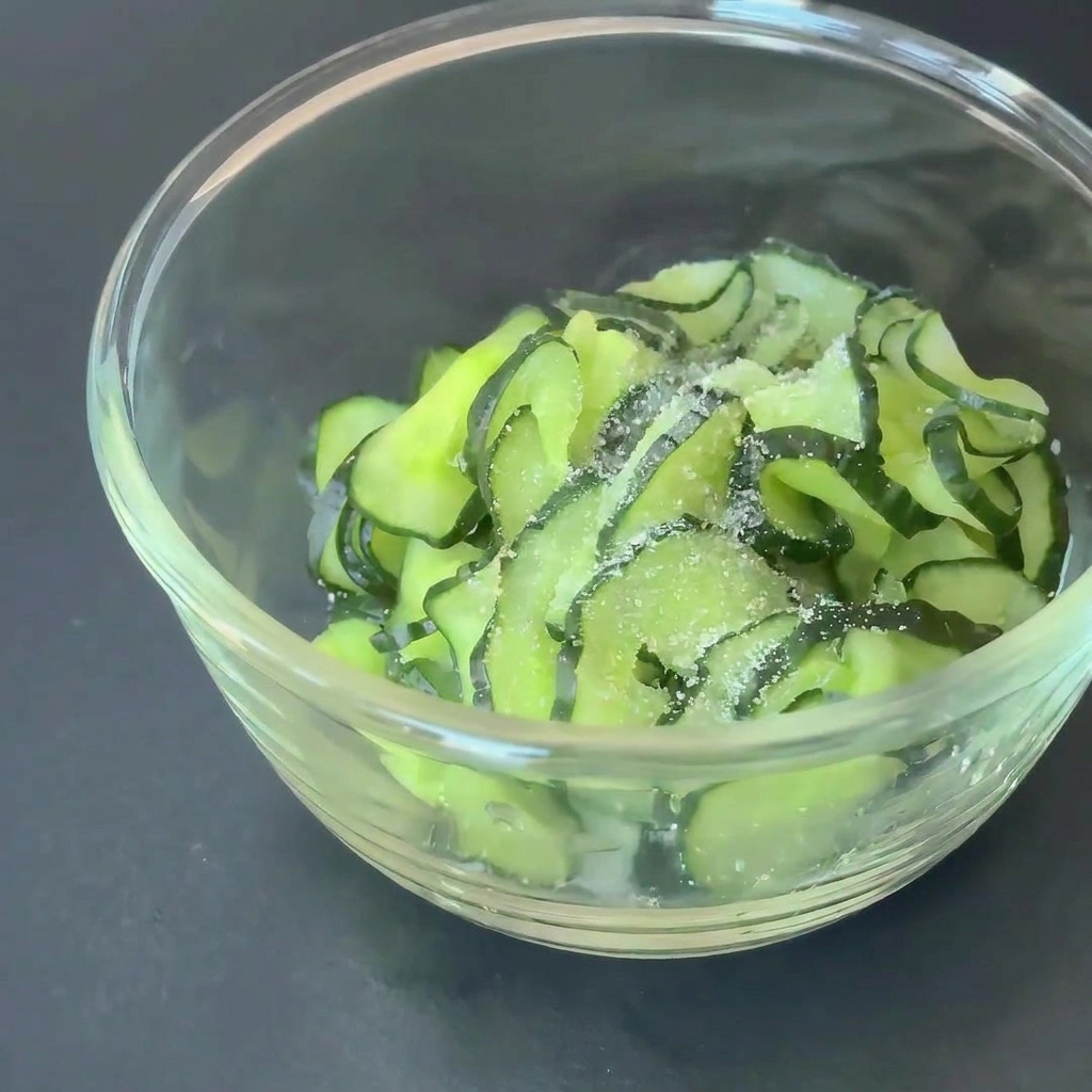 Gurkenscheiben in einer Glasschüssel, gewürzt mit Zucker und Apfelessig.