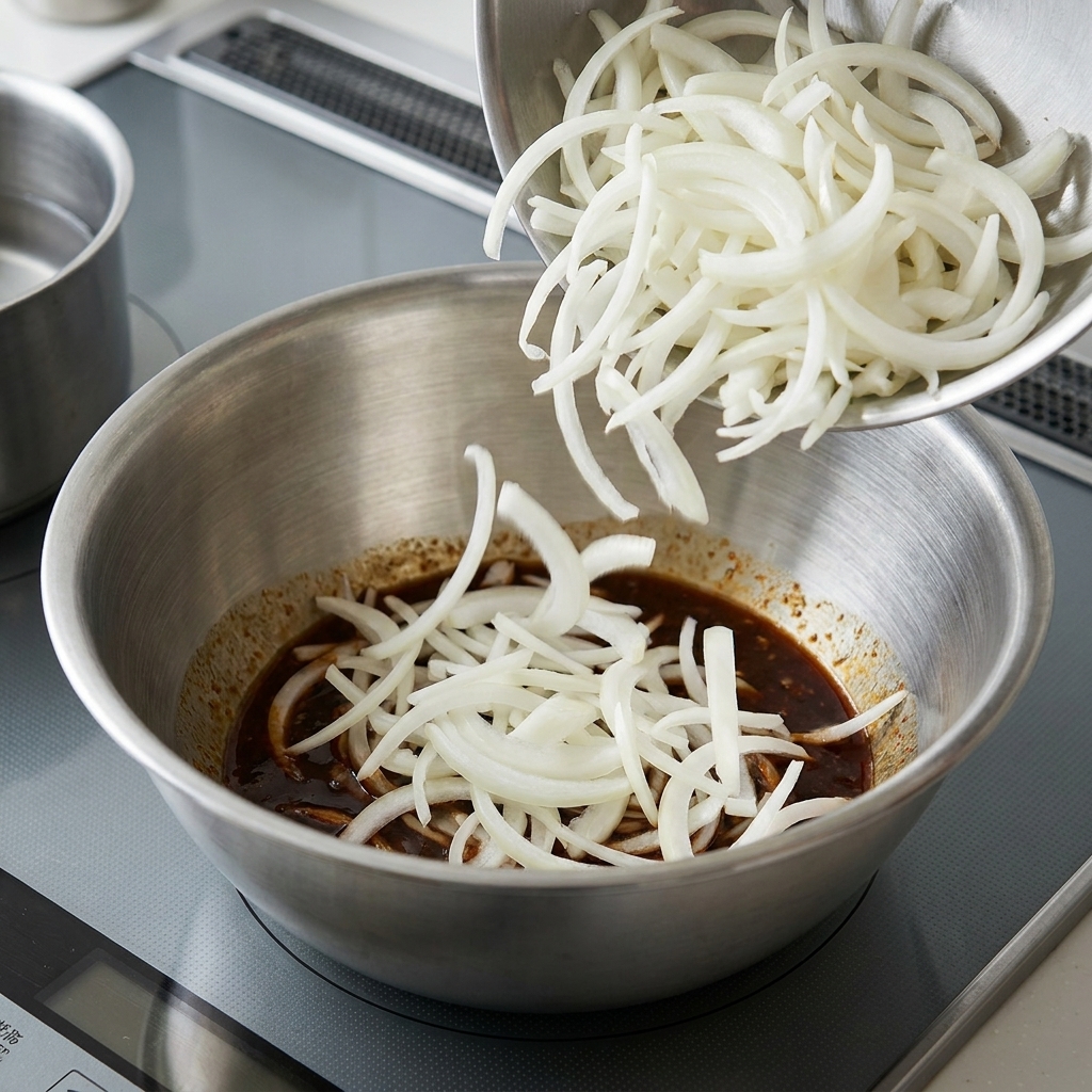 Gekochte Nudeln werden in einer großen Schüssel mit Sesamsauce vermengt.