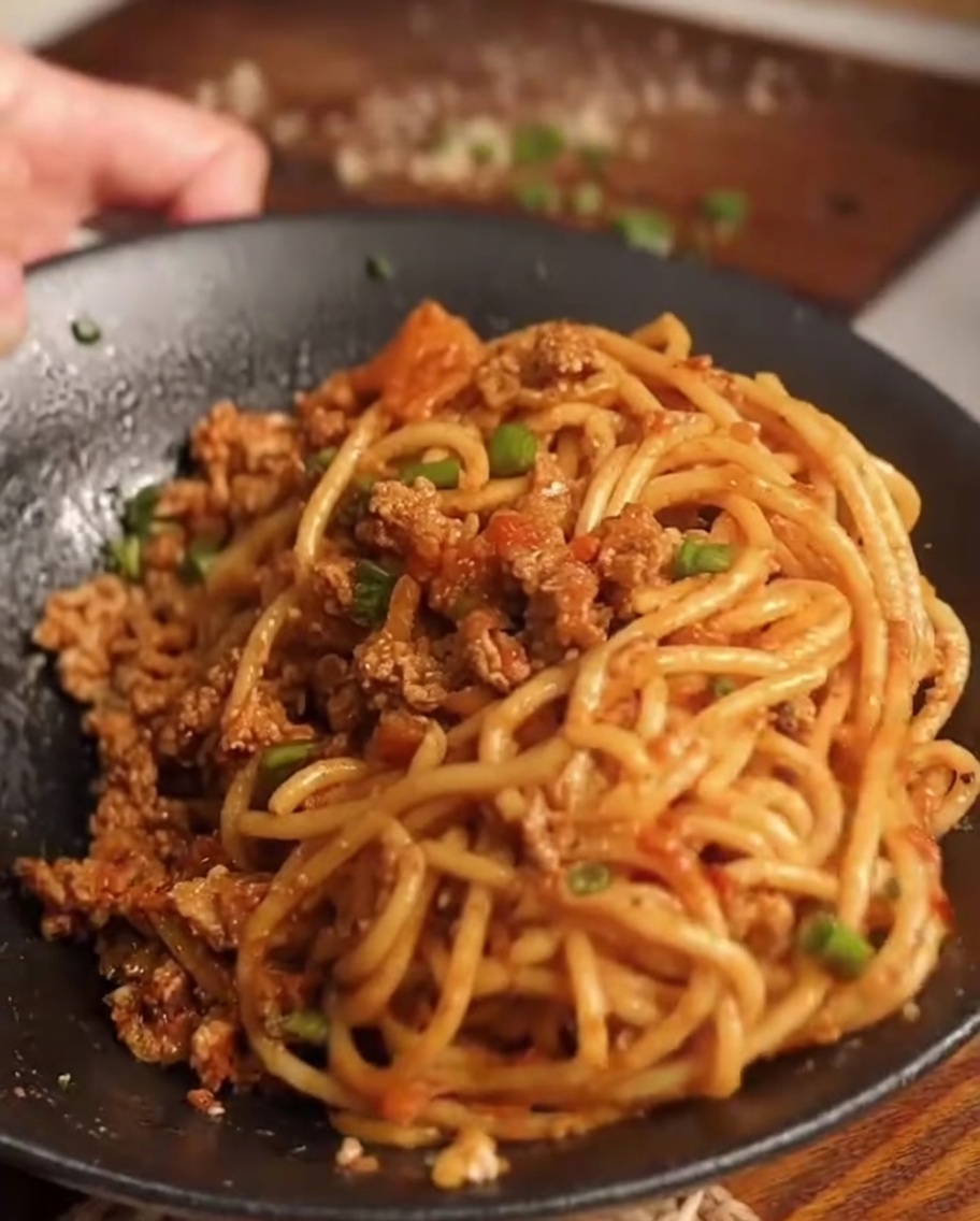 Gekochte Spaghetti werden in die Pfanne mit der Sauce gegeben.