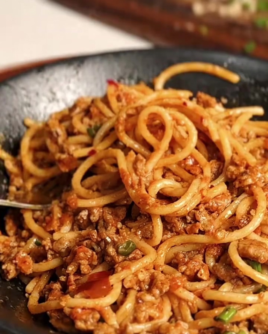 Spaghetti werden in der Pfanne mit der Sauce geschwenkt.