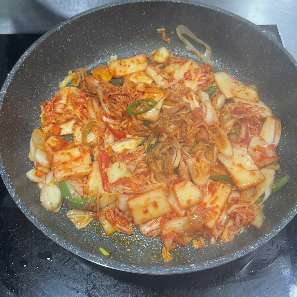 Chilipaste, Sojasauce und Zucker werden zusammen mit Kimchi in die Pfanne gegeben.