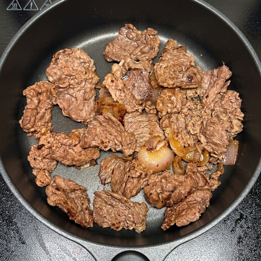 Kimchi-Stücke werden zum Fleisch und den Zwiebeln in die Pfanne gegeben.