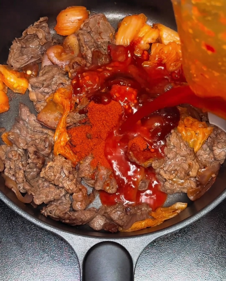 Wasser wird in die Pfanne mit der Rindfleisch-Kimchi-Mischung gegossen.