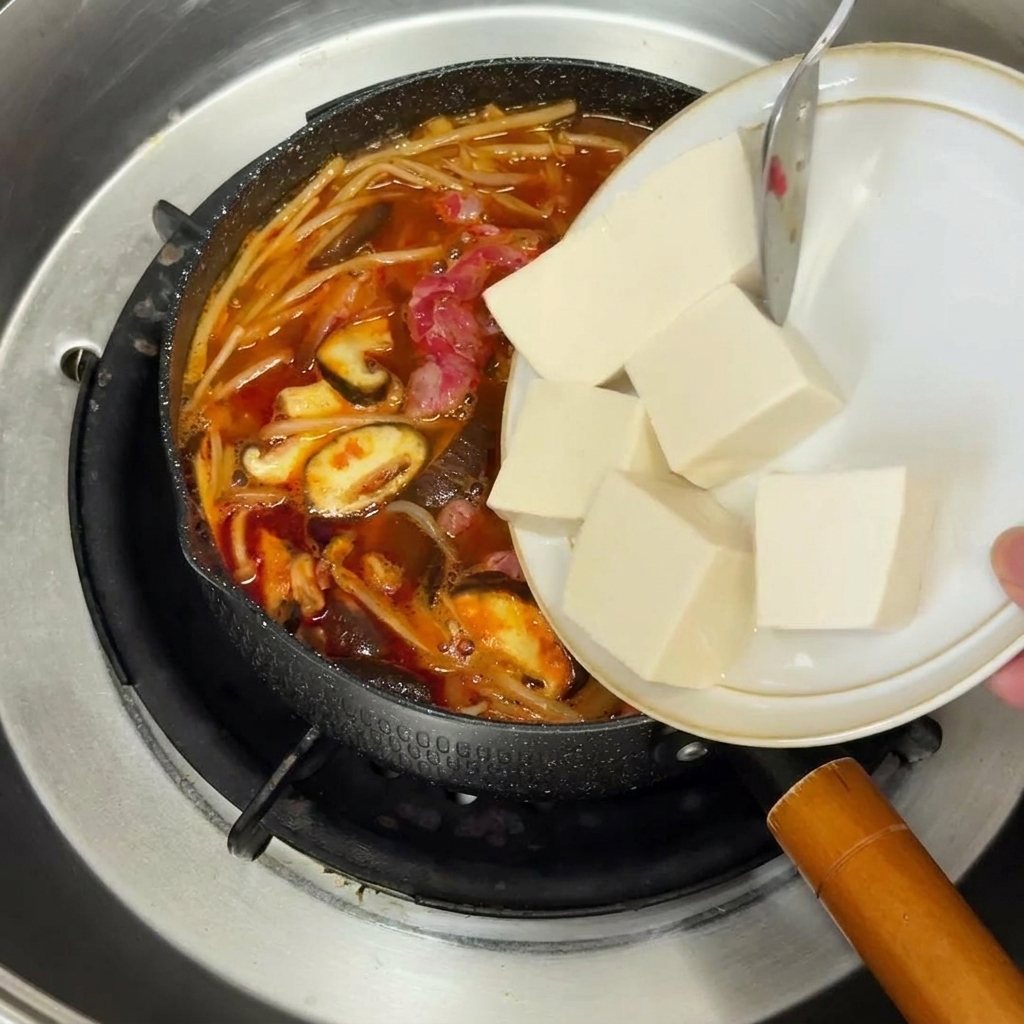 Zwiebelwürfel dünsten in einer gelben Pfanne mit schimmerndem Öl.