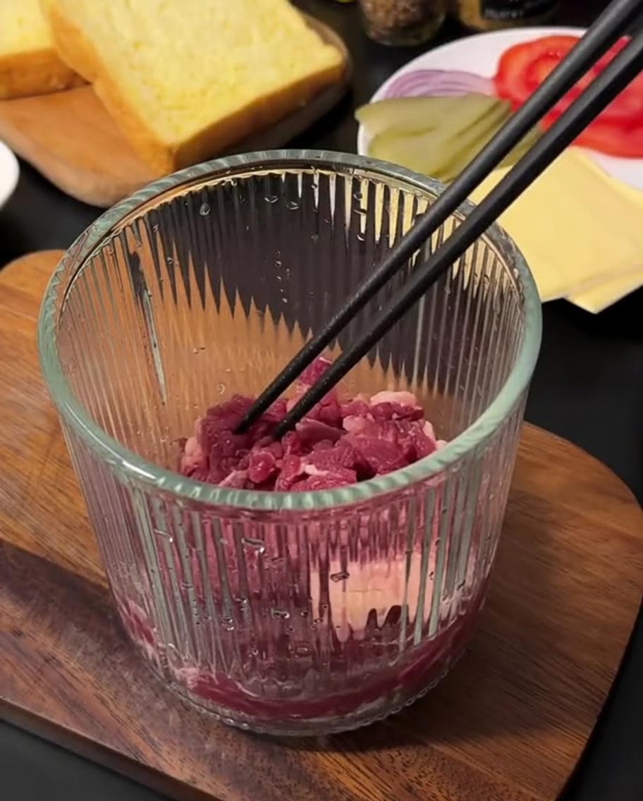 Frisches, rohes Rinderhackfleisch in einem manuellen Zerkleinerer, bereit zur Verarbeitung.