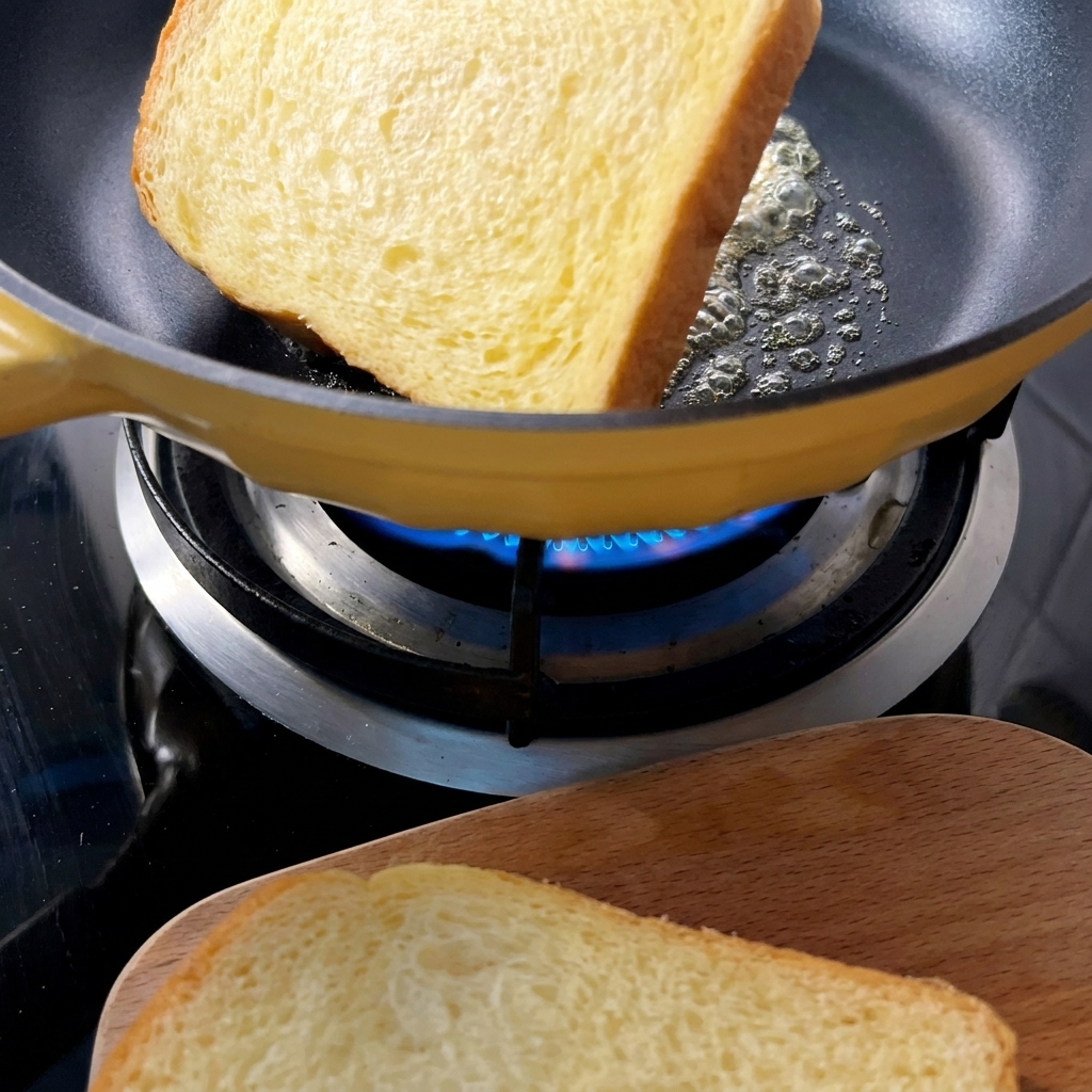Goldbraune Brotscheiben in einer gelben Pfanne mit geschmolzener Butter.