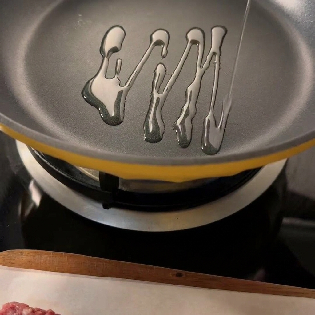 Zwei gewürzte Rinder-Patties braten in einer heißen Pfanne mit sichtbarem Öl.