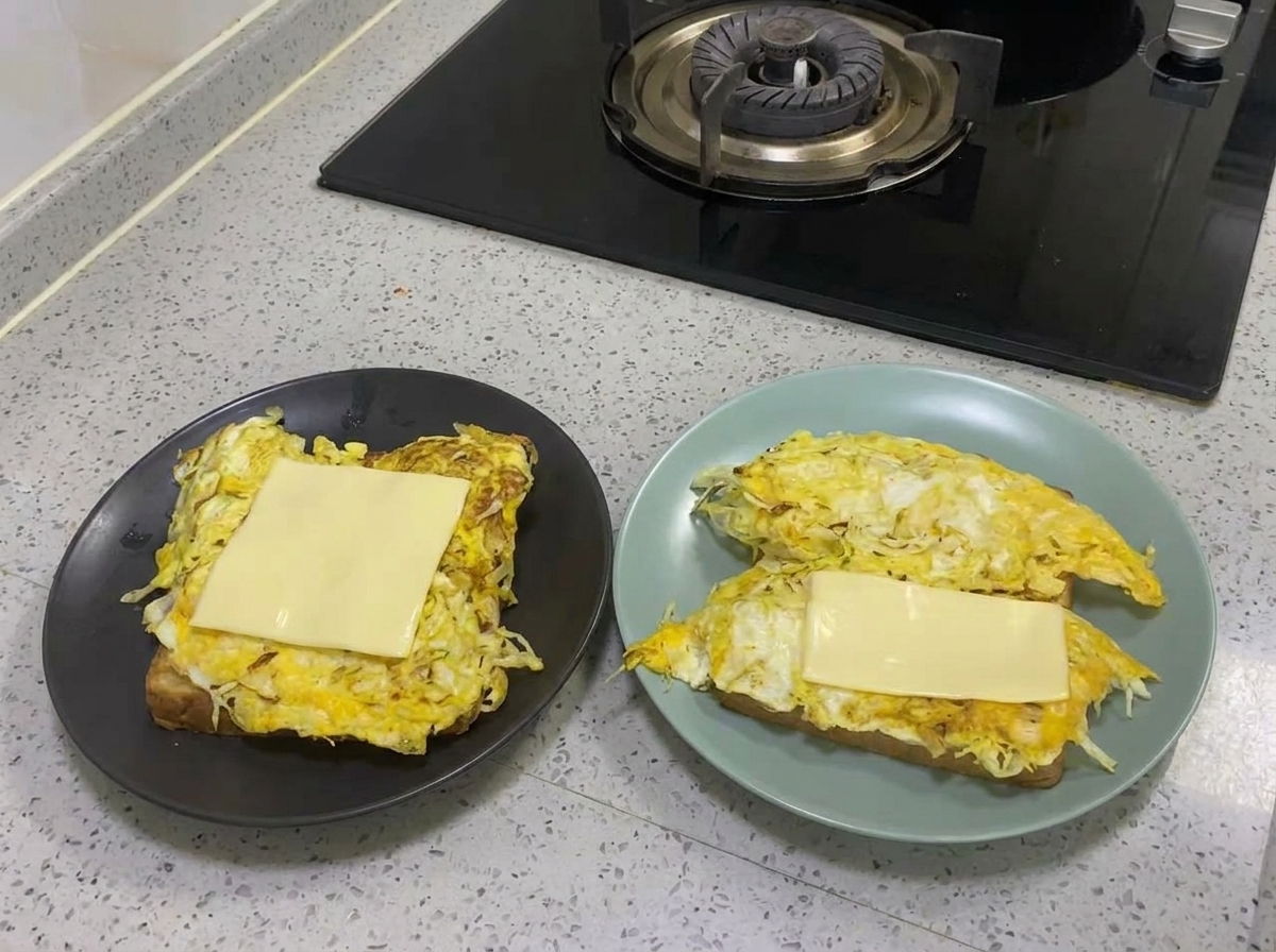 Eine Scheibe Käse schmilzt auf der gebratenen Ei-Kohl-Schicht.