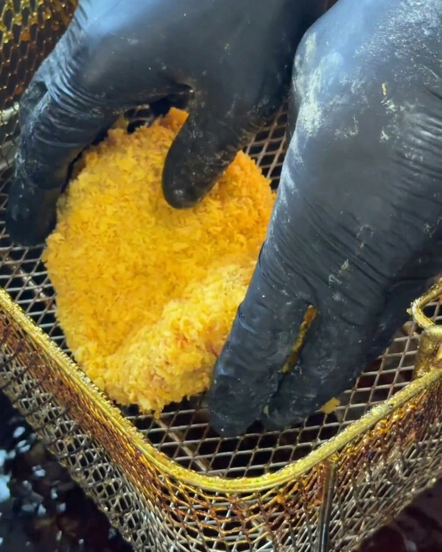 Paniertes Hähnchen wird in heißes Öl gegeben.