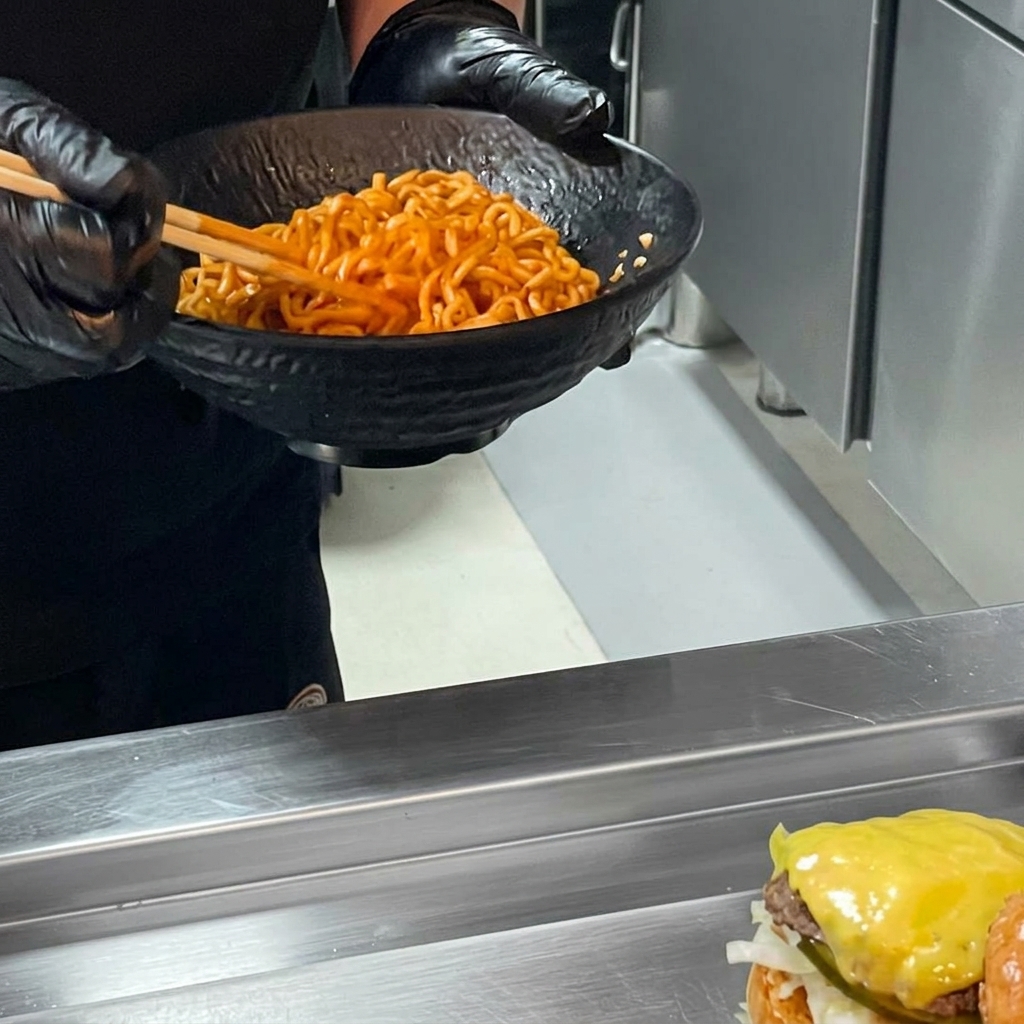 Ein fertiger Ramen-Burger, bei dem ein Nudelberg auf das Patty gelegt und mit dem Brötchendeckel bedeckt wird.