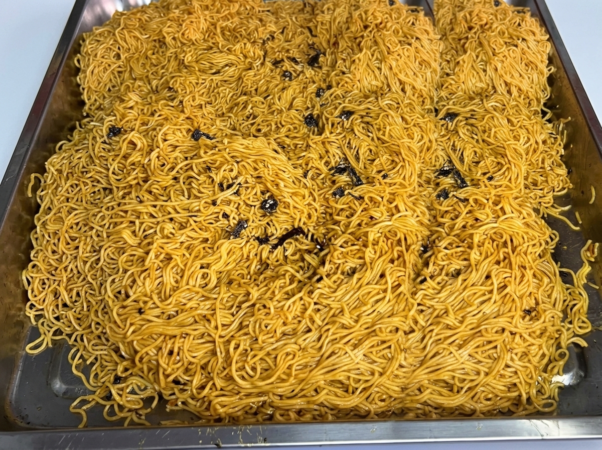 Eine große Portion gekochte Nudeln, verteilt auf einem Edelstahlblech.
