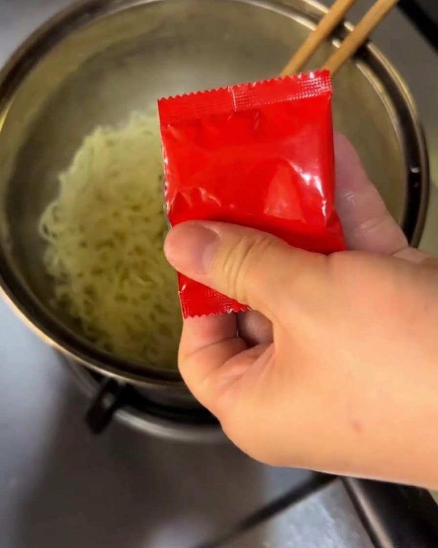 Gewürze und scharfe Sauce in einen Topf mit gekochten Nudeln mischen.