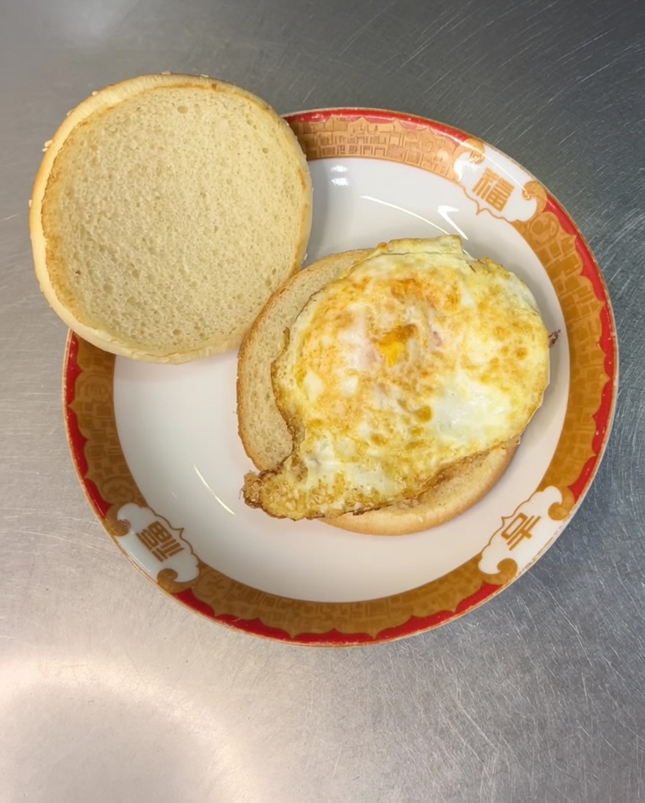 Eine Scheibe Schmelzkäse auf dem Spiegelei im Burgerbrötchen.