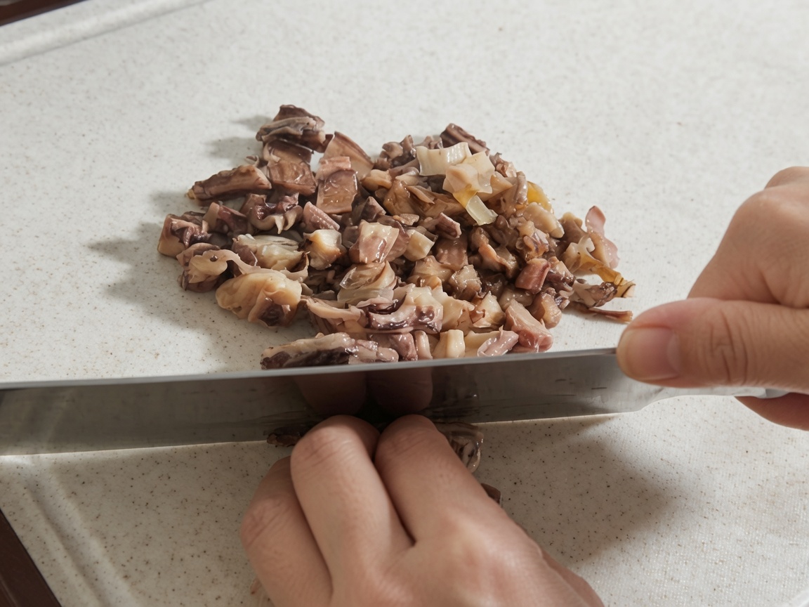 Hände benutzen ein großes Messer, um rehydrierte Shiitake-Pilze und Oktopusstücke auf einem weißen Schneidebrett zu hacken.
