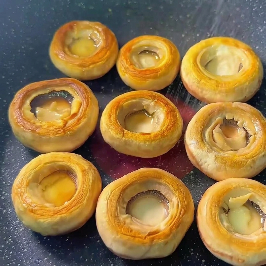 Champignonköpfe in der Pfanne mit Salz und Pfeffer gewürzt.