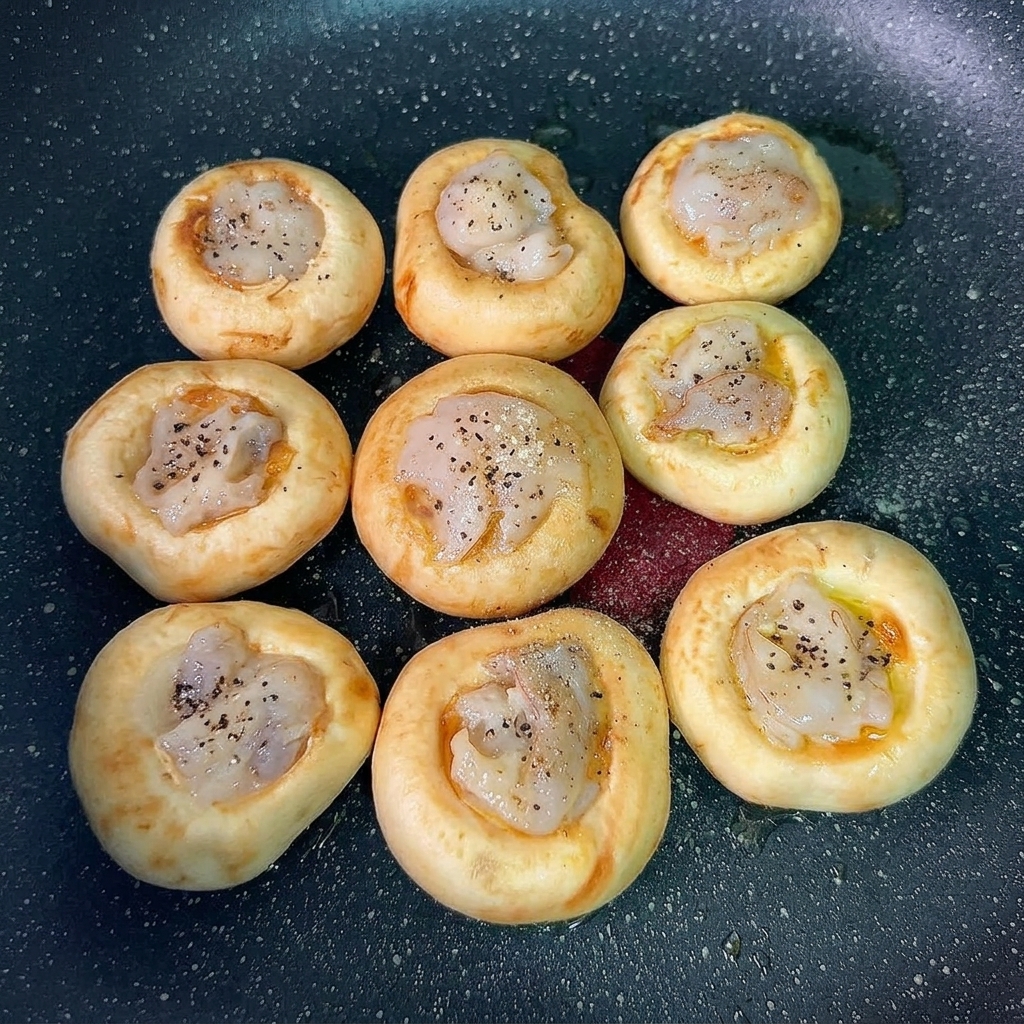 Gewürzte, mit Garnelen belegte Champignonköpfe servierfertig.