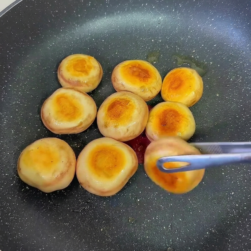 Mit Garnelenpaste gefüllte Champignonköpfe werden zum Bräunen der Unterseite gewendet.