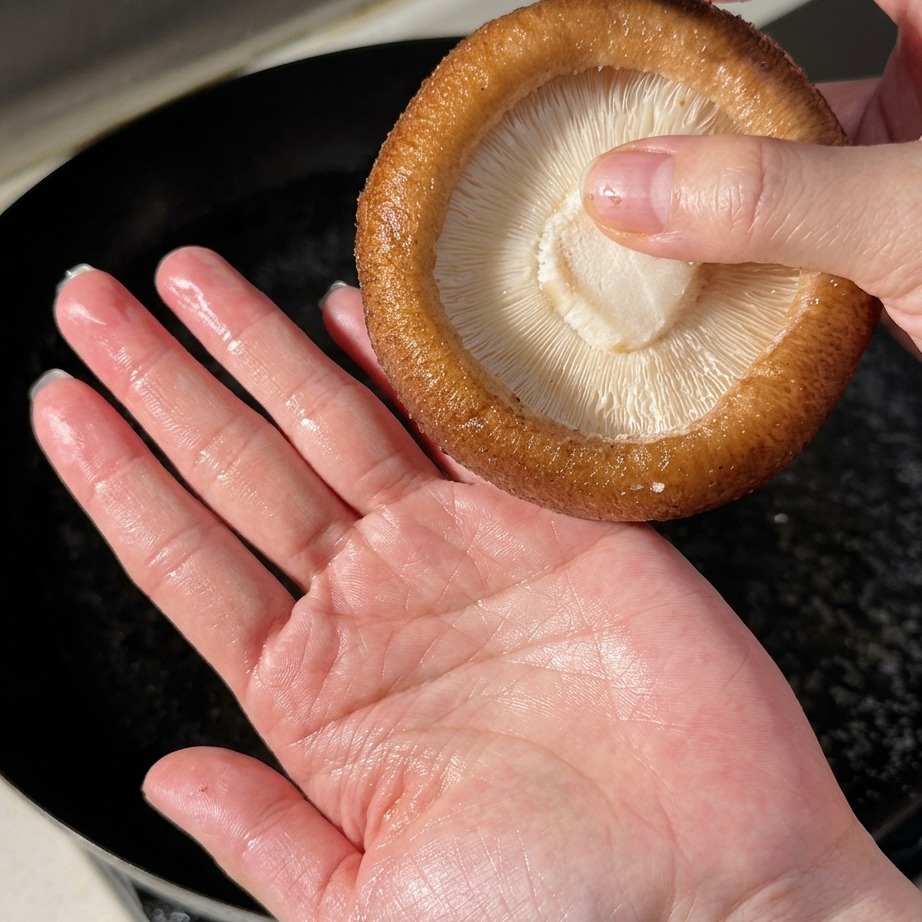 Große Shiitake-Pilze werden in kochendem Wasser blanchiert.
