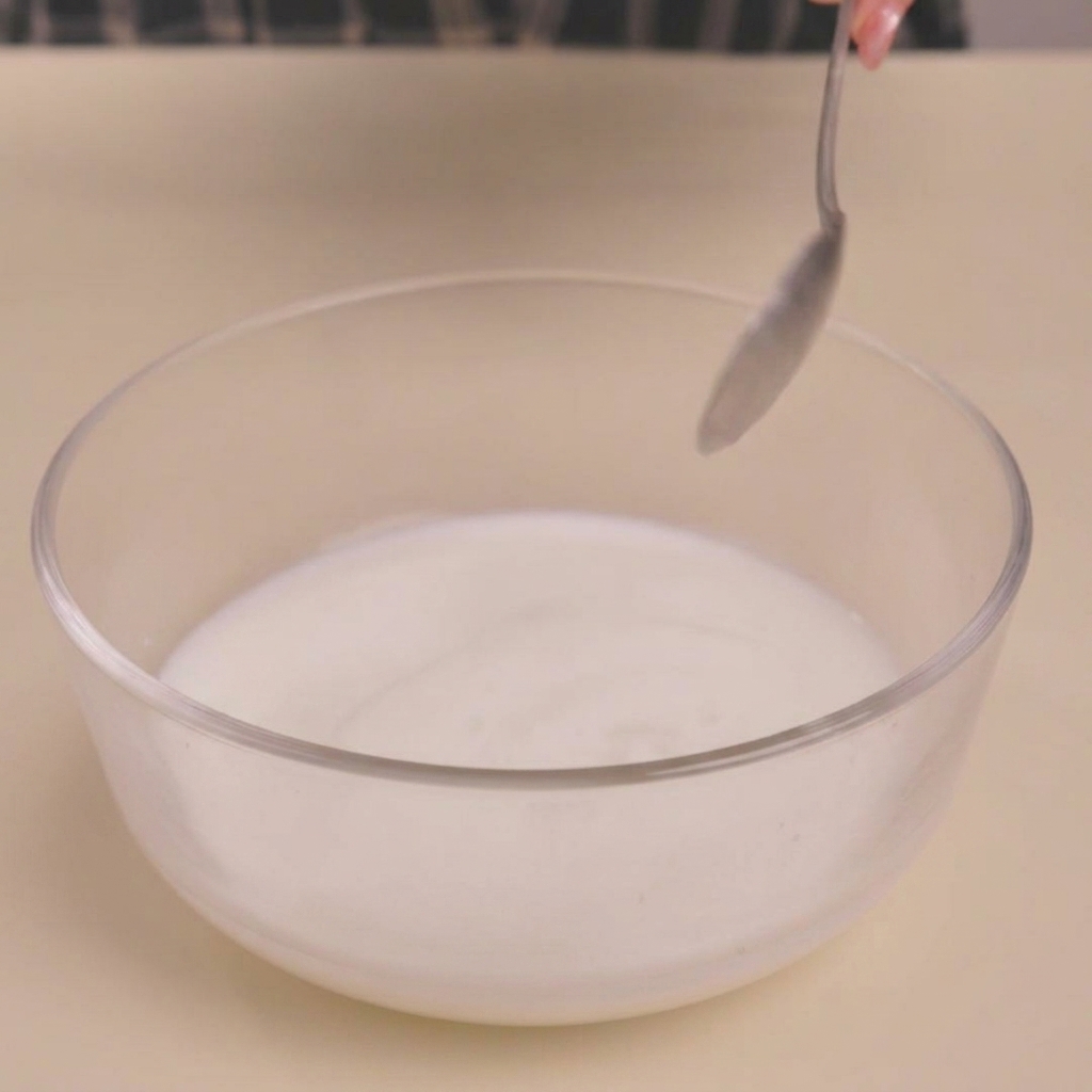 Milch gerinnt in einer Glasschüssel nach Zugabe von Essig und erhält eine buttermilchähnliche Konsistenz.