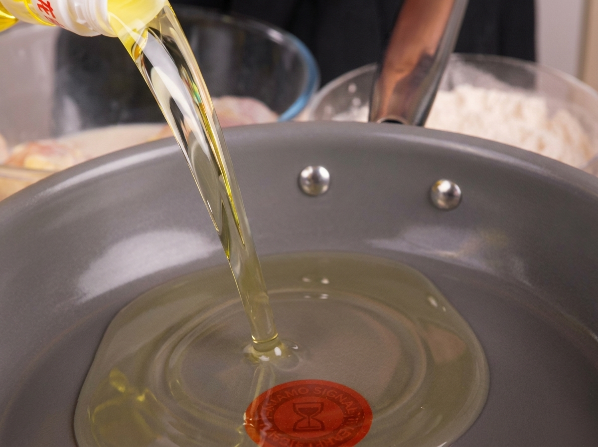 Speiseöl wird in eine tiefe Pfanne gegossen und zum Erhitzen vorbereitet.