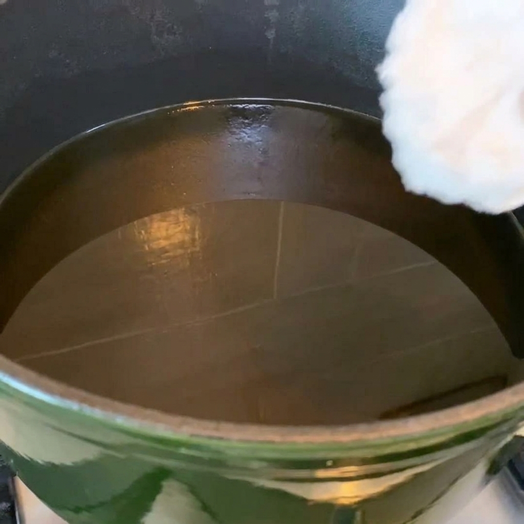 Hähnchenflügel in einer Pfanne mit heißem Öl, die eine goldbraune Farbe annehmen.
