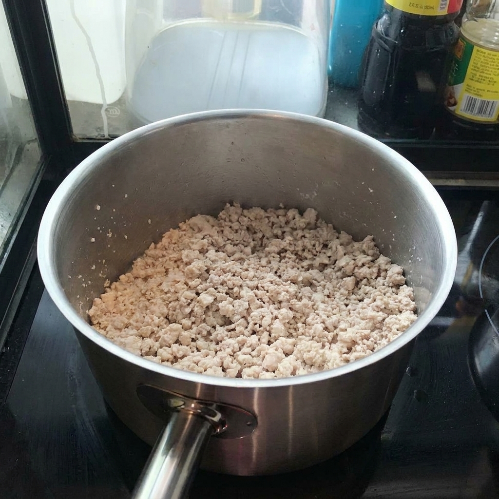 Hackfleisch bräunt in einem Topf und wird mit einem Pfannenwender verrührt.