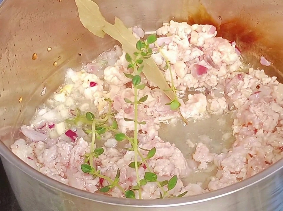 Frische Thymianzweige und ein Lorbeerblatt werden zum Hackfleisch im Topf gegeben.