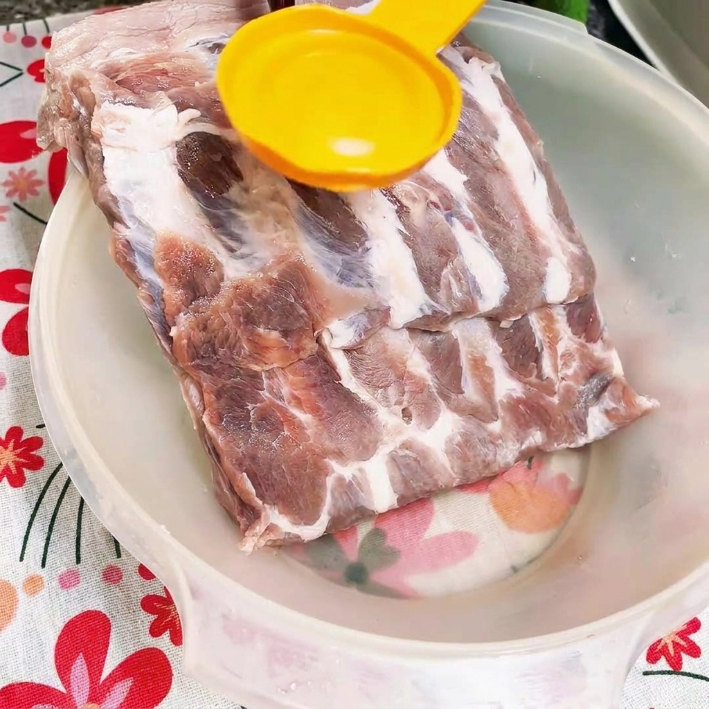 Dunkle Austernsauce wird in eine Schüssel mit rohen Rippchen gegossen.