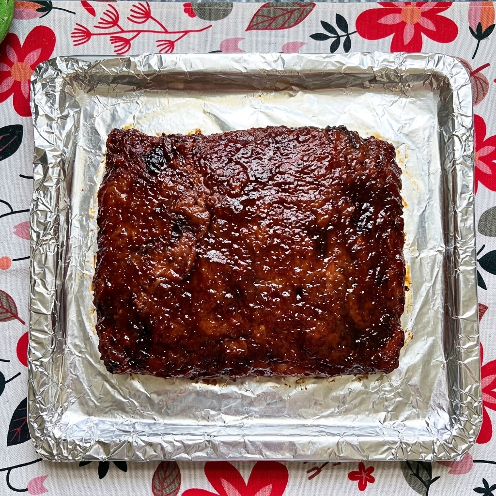 Gekochte Rippchen werden mit der dunklen Sauce eingepinselt.