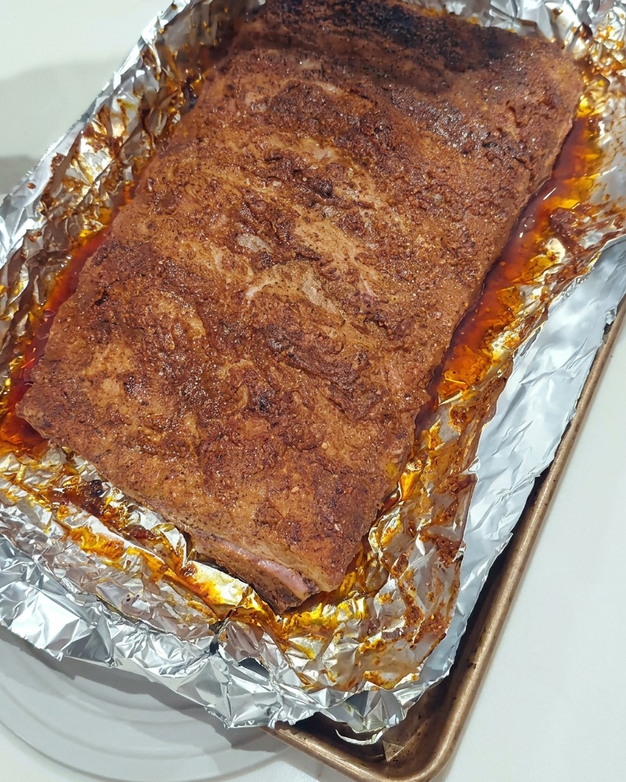 Ein Silikonpinsel bestreicht die gegarten Rippchen mit frischer BBQ-Sauce.