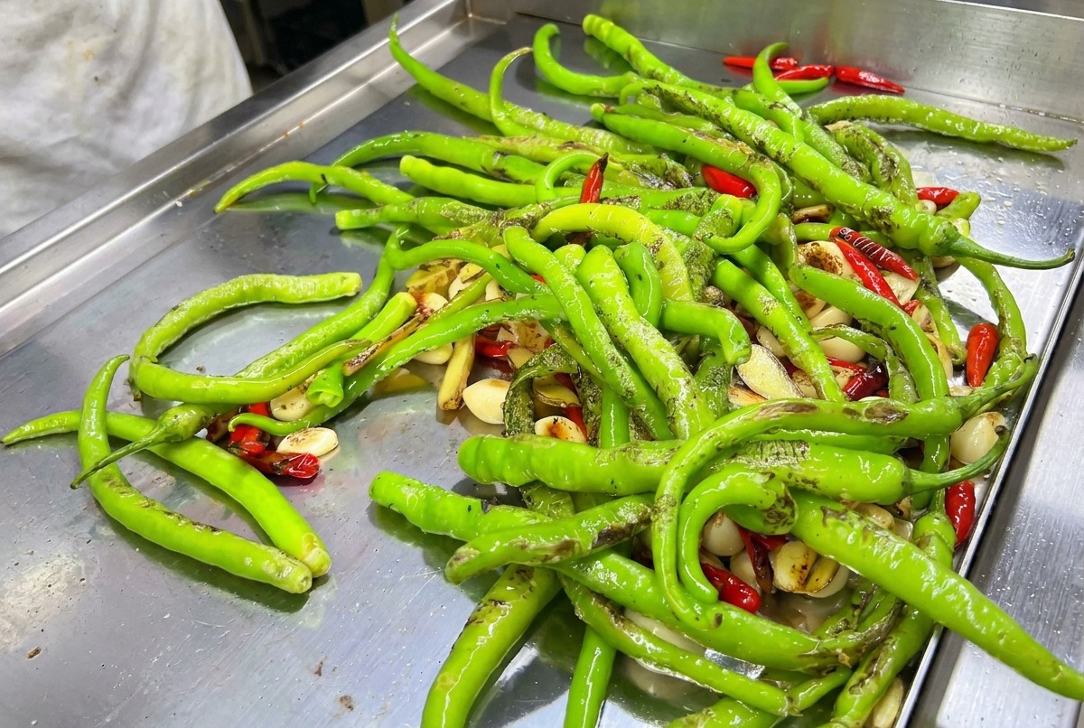 Eine Mischung aus grünen und roten Chilis auf der heißen Grillplatte.