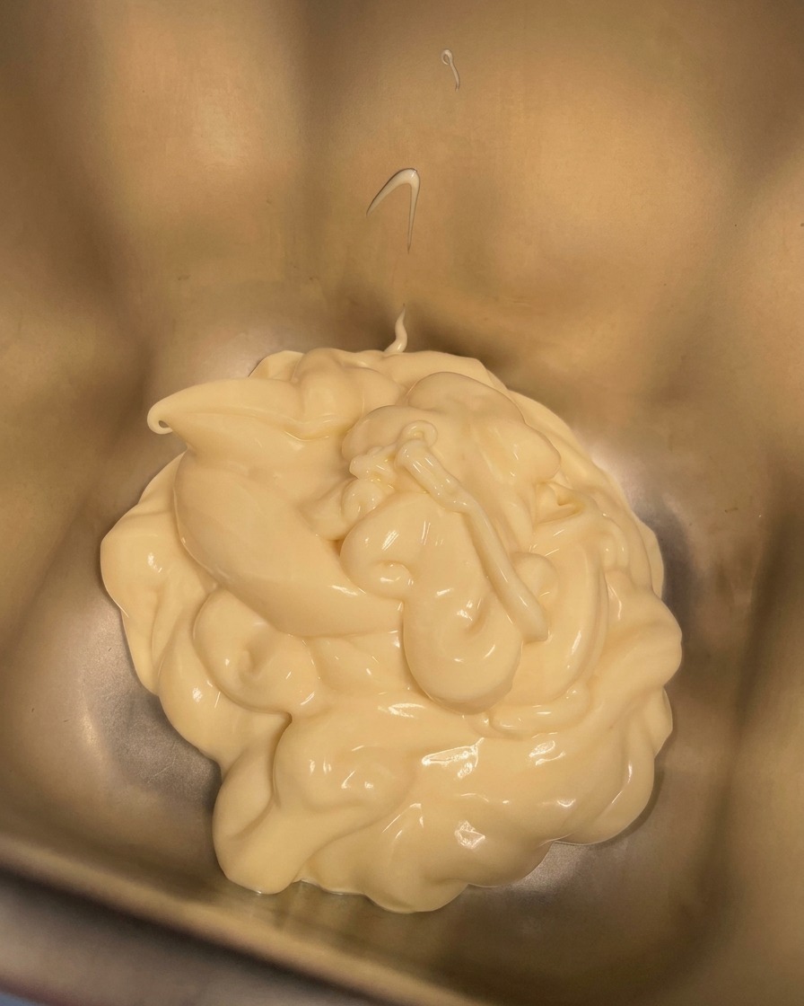 Sahne wird in einen Metallbehälter mit Mayonnaise gegossen.