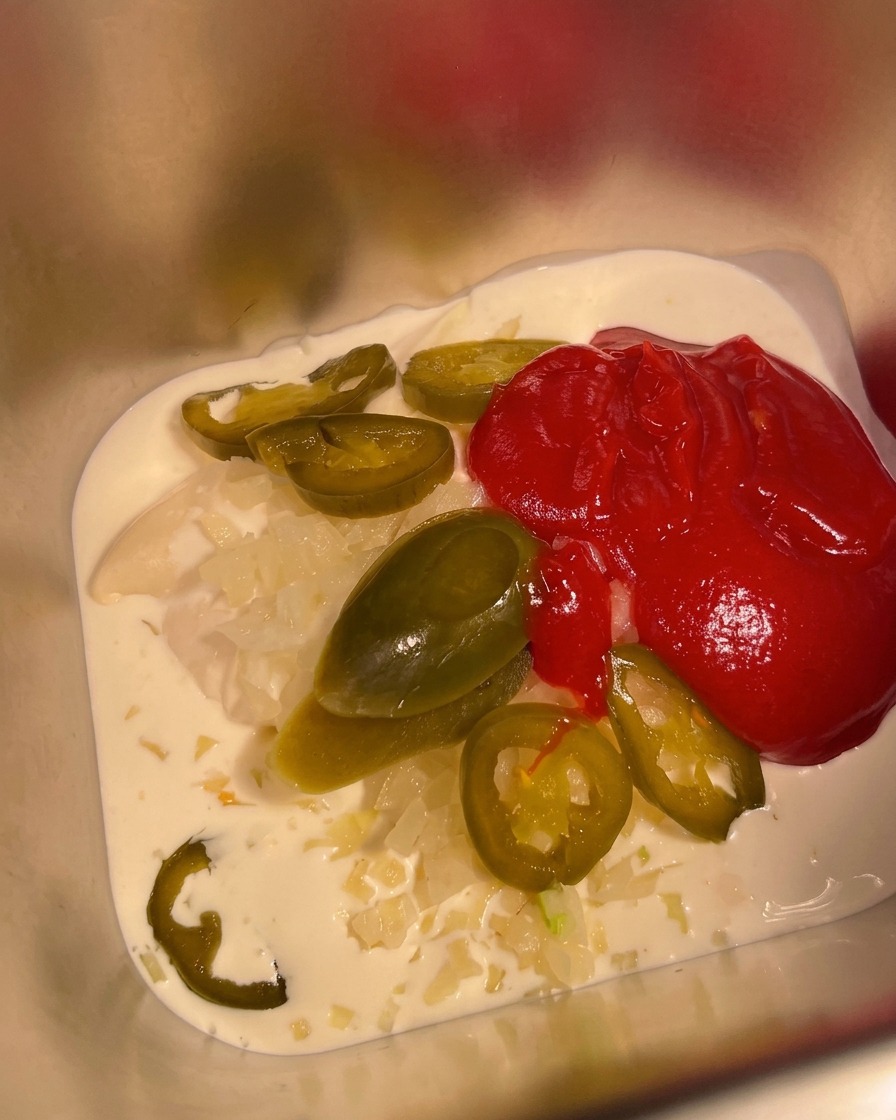 Mexikanische scharfe Soße wird in den Behälter mit der Mayo-Basis gegeben.