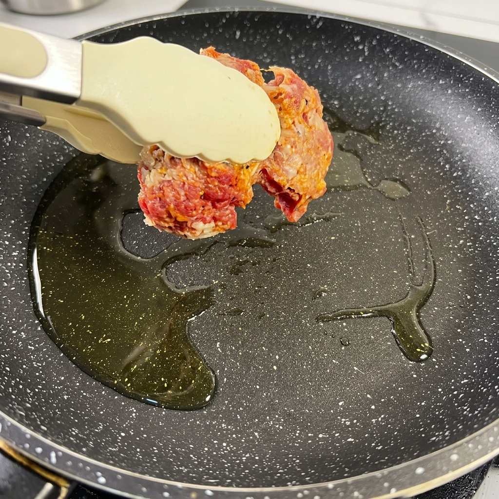 Gewürzte Rinderbruststücke, die in einer heißen Pfanne mit Öl goldbraun angebraten werden.