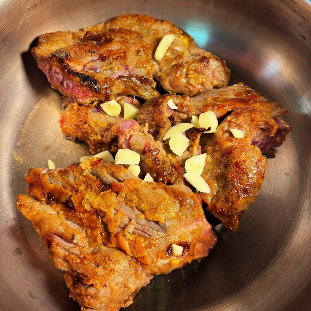 Angebratenes Rindfleisch im Schnellkochtopf, ergänzt durch gehackten Knoblauch und Zwiebeln.