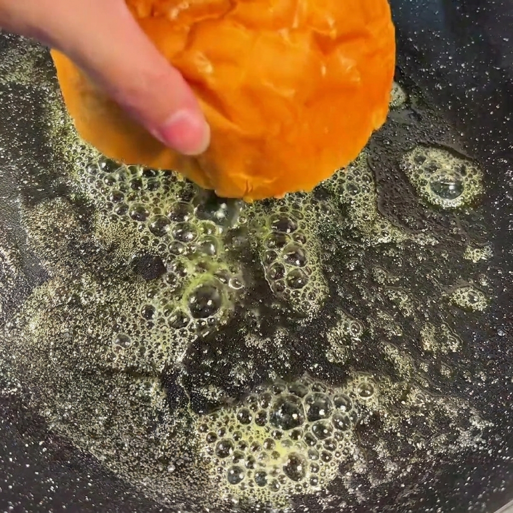 Burgerbrötchenhälften mit der Schnittfläche nach unten in einer Pfanne mit geschmolzener Butter.