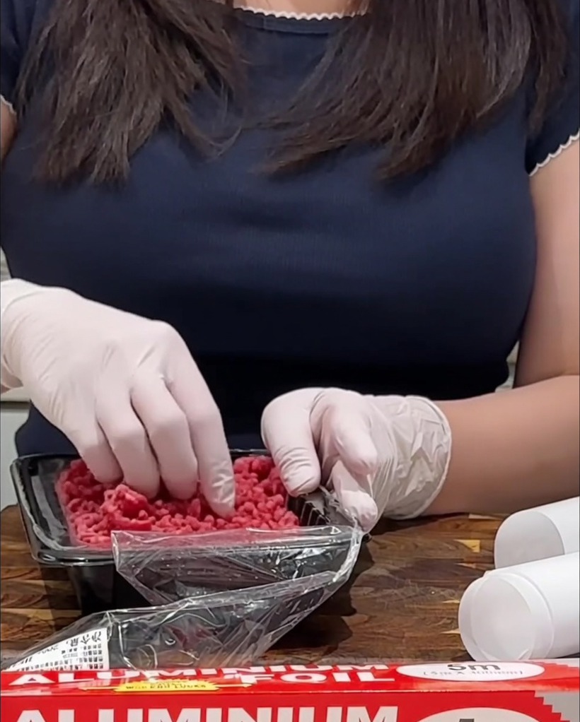 Rohe Hackfleisch-Patties werden auf einem Holzbrett mit Salz und Pfeffer gewürzt.