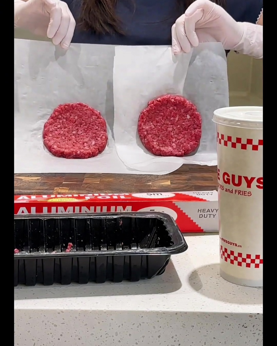 Das Rinder-Patty wird mit einem Pfannenwender in der Pfanne gewendet.