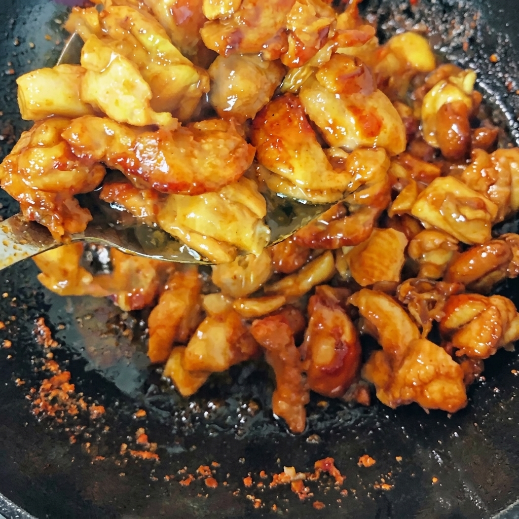 Angebratenes Hähnchen wird im Wok mit Frühlingszwiebeln, Ingwer und getrockneten Chilis geschwenkt.