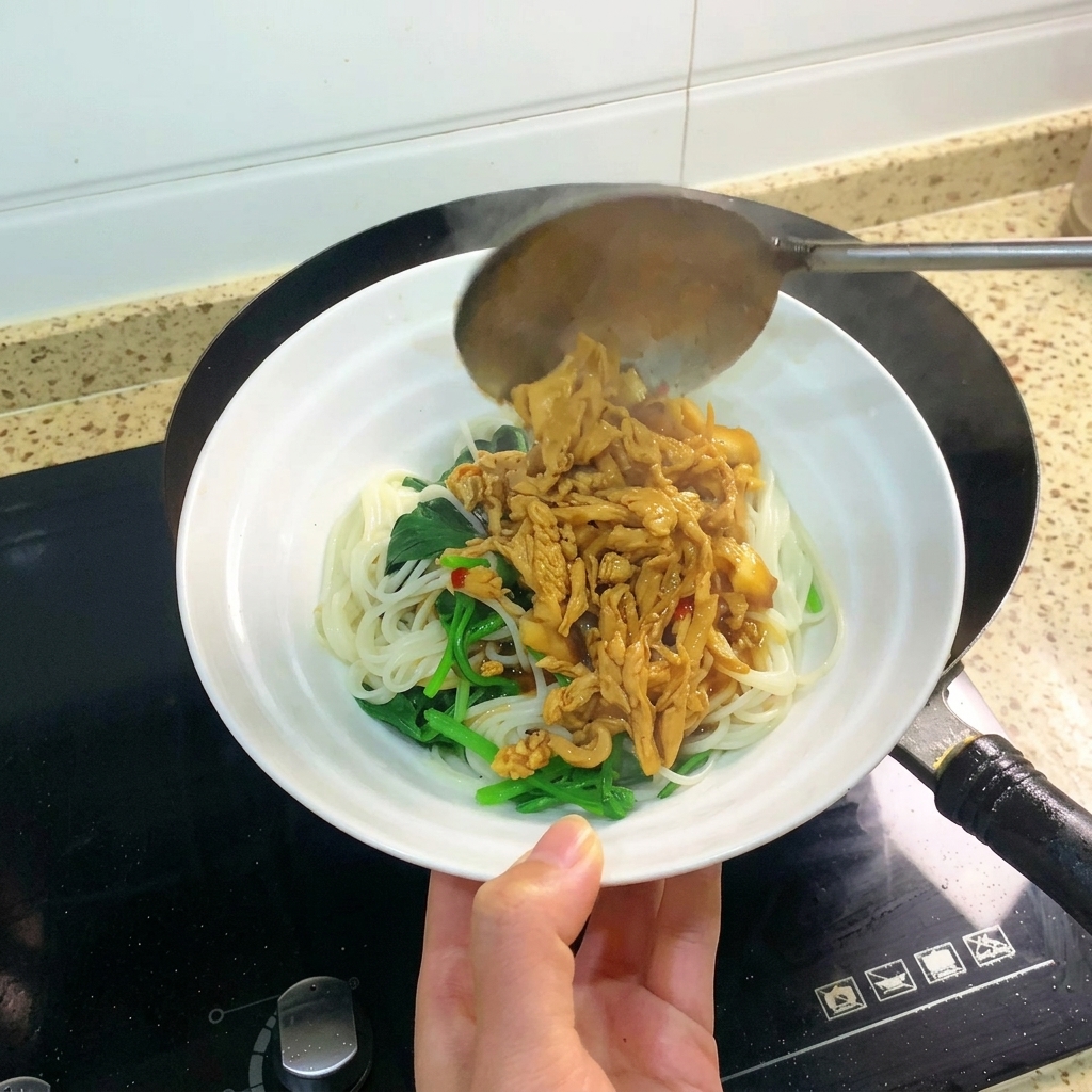 Eine Schöpfkelle gibt Hähnchen und Sauce über eine Schüssel mit Nudeln.