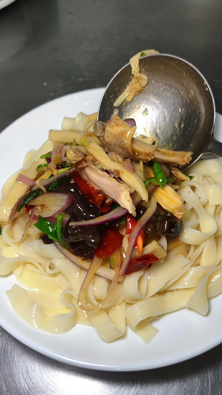 Ein aromatischer Teller mit Xinjiang-Pfeffernudeln, verfeinert mit Chiliöl, zartem Hähnchen und knackigem frischen Gemüse.