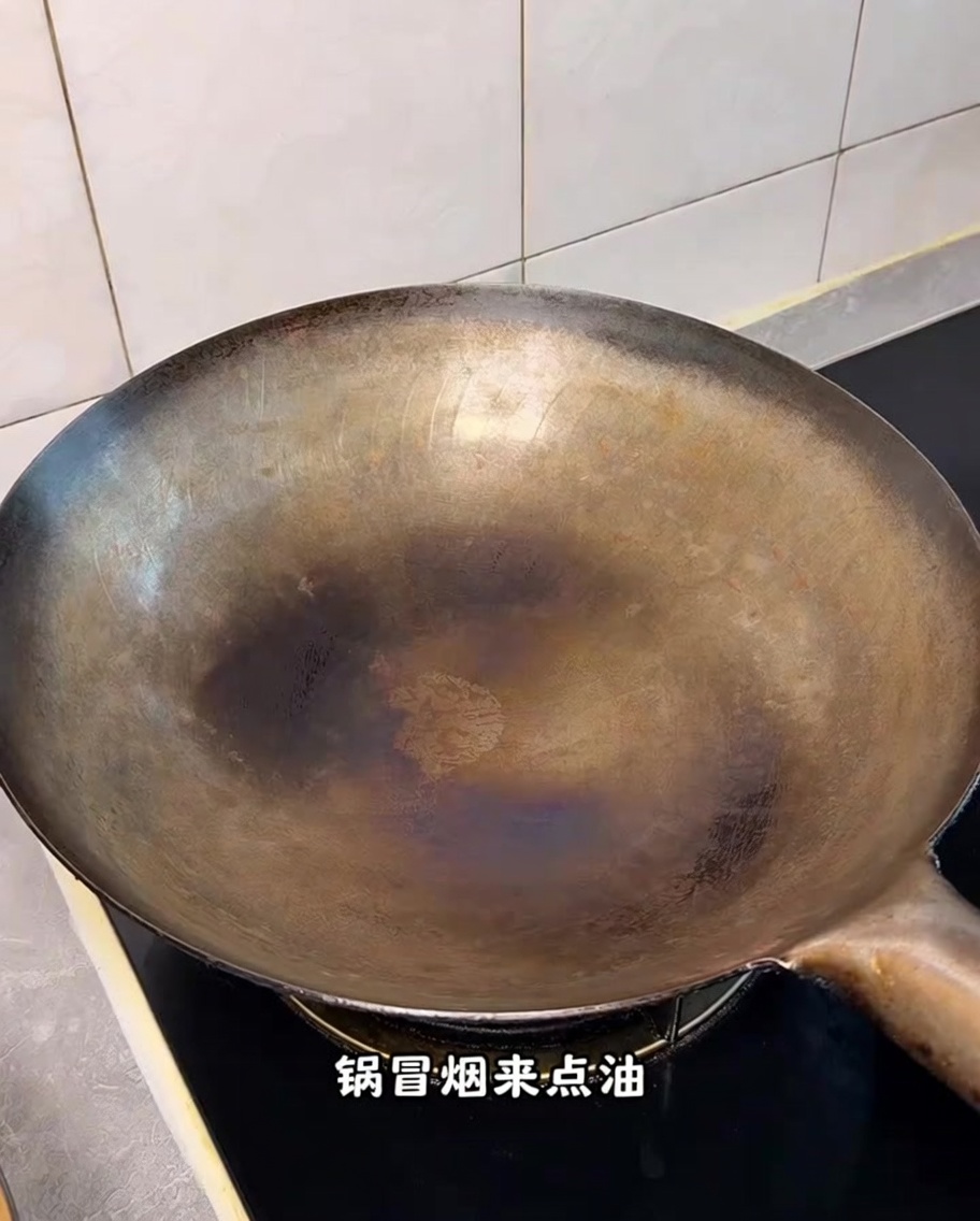 Ein heißer, eingebrannter Wok auf dem Herd mit sichtbaren Rauchschwaden.