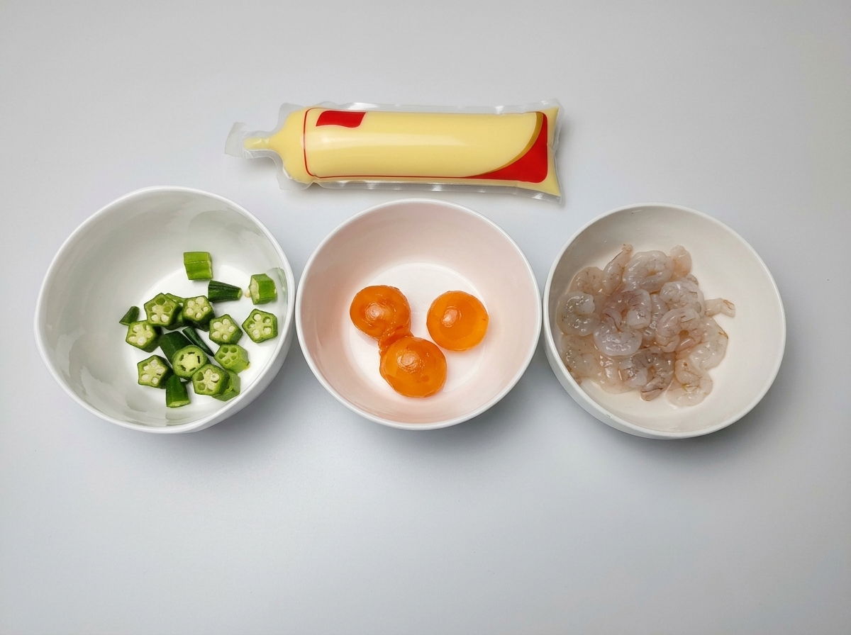 Drei weiße Schalen mit geschnittener Okra, gesalzenem Eigelb und rohen Garnelen neben einer Packung Eiertofu.