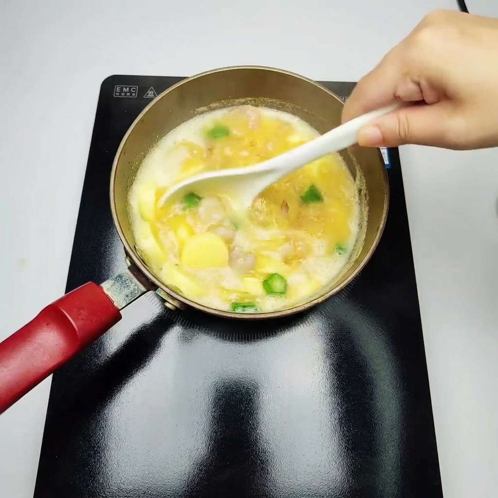 Eine weiße Schöpfkelle rührt vorsichtig eine simmernde gelbe Suppe mit Garnelen, Okrastücken und Eiertofu um.