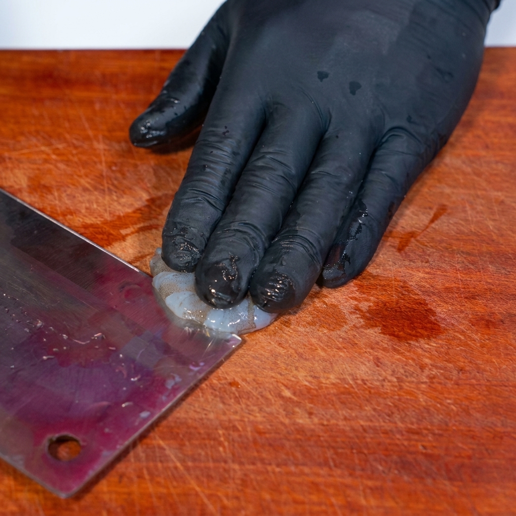 Mit einem Messer wird der Rücken einer Garnele leicht eingeschnitten, um den Darm zu entfernen.