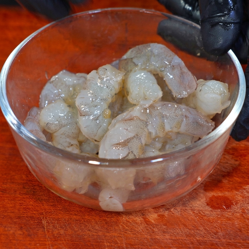 Garnelen marinieren in einer Glasschüssel mit Gewürzen und Speisestärke.