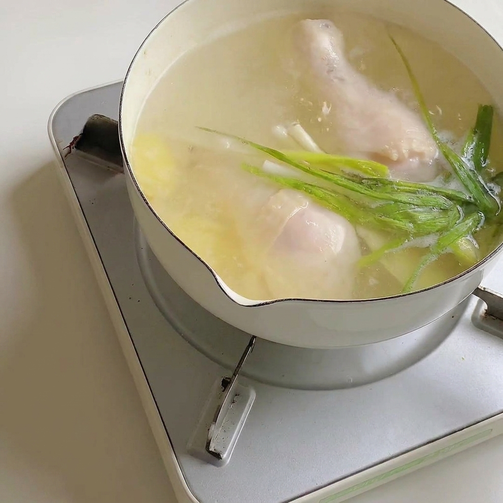 Ramen-Gewürzpulver wird in den Topf mit der Brühe und dem Hähnchen gerührt.